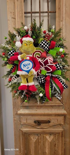 a christmas wreath on top of a wooden cabinet in front of a door with the letter n o