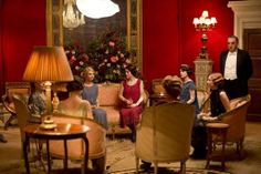 a group of people sitting around a living room with christmas tree in the back ground