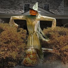 a scarecrow statue with two jack o lantern pumpkins in front of a house