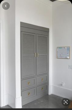 an empty room with two large gray closets and a wooden bench in the corner