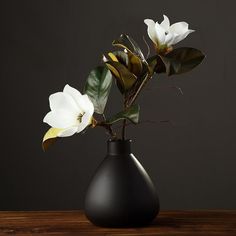 a black vase with white flowers in it