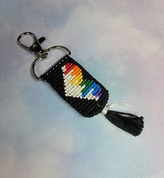 a keychain with a multicolored cross stitch pattern on it and a tassel