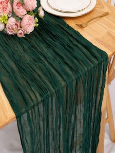 a green table runner with pink flowers on it next to a white plate and silverware