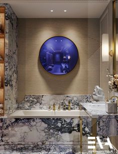 a bathroom with marble walls and flooring has a blue circular mirror above the bathtub