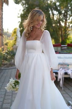 a woman in a white dress is walking down the street