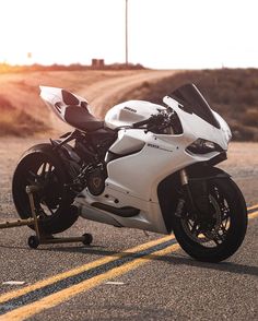 a white motorcycle is parked on the side of the road with its front tire up