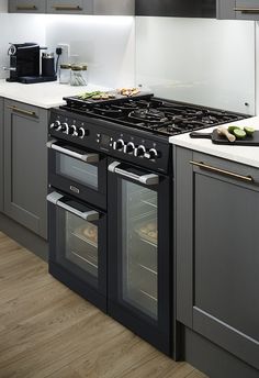 a kitchen with an oven, stove and counter tops in grey cabinets next to a coffee maker