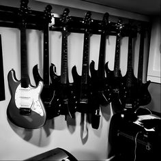 black and white photograph of guitars hanging on wall