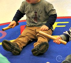 two young boys sitting on the floor playing with baseball bats