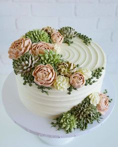 a white cake with flowers and succulents on top