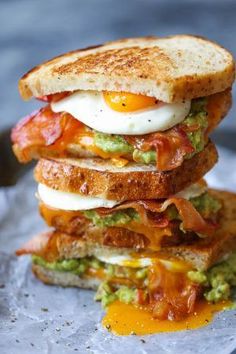 a bacon, egg and avocado sandwich is stacked on top of each other