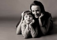 a woman and child laying on the floor posing for a black and white photo together