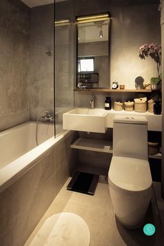 a bathroom with a white toilet sitting next to a bath tub under a mirror on the wall