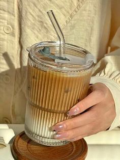 a woman holding a cup with a straw in it on top of a wooden stand