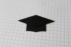 a piece of paper with a black graduation cap on it and graph paper in the background