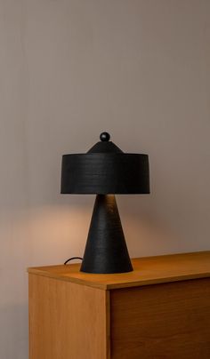 a black lamp sitting on top of a wooden dresser