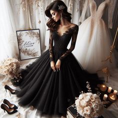 a woman in a black dress standing next to some wedding gowns