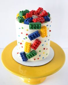 a birthday cake decorated with legos and confetti on a yellow platter