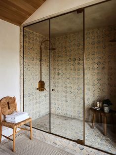 a room with a chair, shower and wallpaper