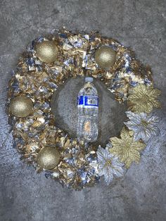 a water bottle sitting on top of a wreath with gold ornaments around it's edges