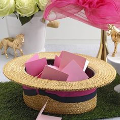 a straw hat sitting on top of a green grass covered ground next to flowers and other decorations