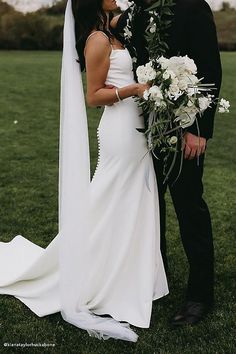 a bride and groom standing in the grass