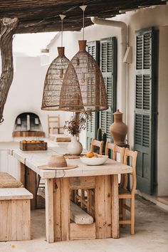 an outdoor dining area with table, chairs and baskets hanging from the ceiling over it