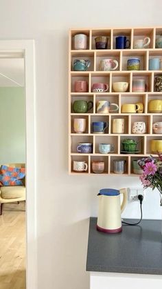 a vase with flowers in it sitting on a counter next to a wall mounted shelf