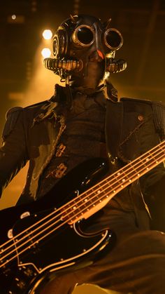 a man in a gas mask playing a bass guitar