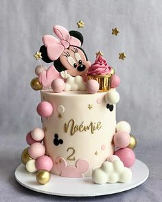 a minnie mouse birthday cake with pink frosting and gold stars on top, sitting on a white plate