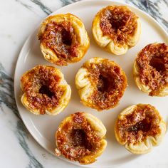 small pastries on a white plate with red sauce in the middle and toppings