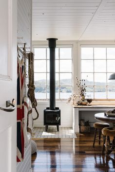 an open kitchen and dining room with wood flooring, white walls, and large windows