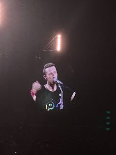 a man standing in front of a microphone on top of a stage with lights behind him