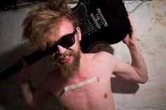 a shirtless man holding an electric guitar