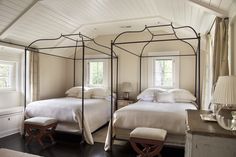 two beds in a bedroom with white linens and pillows on top of each bed