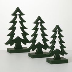 three small green christmas trees sitting on top of a white table next to each other