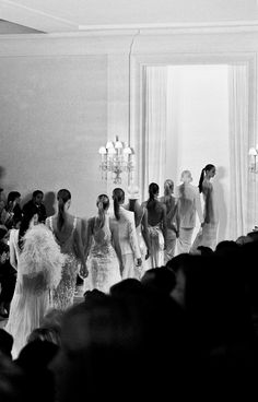 a group of women walking down a runway in front of a crowd at a fashion show