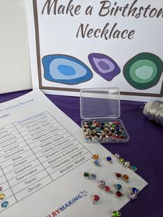 a table topped with lots of beads next to a sign that says make a birthday necklace