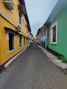 an empty street lined with colorful buildings in front of each other on a cloudy day