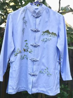 "Treat yourself or that special someone to this gorgeous light blue hand painted asian blouse with mandarin collar and frog closure asian shirt. Really pretty asian oriental blouse with long sleeve that appears to have minimum wear, very good, clean condition. Stylish woman silk blouse vintage top is great for all seasons. The chinese top woman shirt approximately measures when laying folded: from pit to pit- 19.5\" sleeve length-19\" length-24.5\" ( measuring from nap of neck to bottom edge down the back) Elegant asian clothes might be birthday gift for woman, silk women shirt for Valentines day gift for her, chinese blouse as an anniversary gift for wife, mandarin collar frog closure vintage silk top for Mother's day gift for mom, silk blouse for New Years or Christmas gift for women, as Embroidered Long Sleeve Light Blue Blouse, Spring Top With Stand Collar, Fitted Blue Top With Stand Collar, Traditional Relaxed Fit Shirt For Spring, Blue Traditional Shirt For Spring, Traditional Blue Shirt For Spring, Fitted Stand Collar Blouse For Summer, Spring Tops With Stand Collar And Relaxed Fit, Spring Tops With Stand Collar In Relaxed Fit