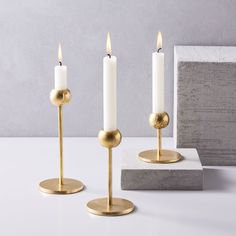 three candles are sitting on top of a white table next to a gray and gold box