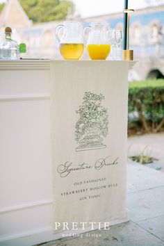 two glasses of orange juice sit on top of a towel next to an outdoor bar