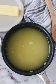 a pan filled with green liquid next to a wooden spoon