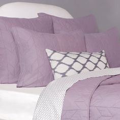 a bed with purple comforters and pillows