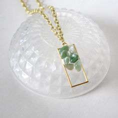 ̩̩͙✩ Handmade gold colored necklace with green aventurine pendant ✩*̩̩͙*˚ Overview: ⋆ 1.75 x 0.75 inch pendant with green aventurine crystals in resin-cast rectangular frame ⋆ 20 inch gold colored chain with lobster clasp closure and large connector loop  ⋆ Handmade and original design ⋆ Believed to bring good luck ⋆ Heart chakra This pendant is made of tiny tumbled aventurine crystals sealed in a durable, clear resin window. The crystals partially extend beyond the resin on the front side and the back surface of the pendant is flat for ease of wear. The 20 inch/51 cm chain is made of iron/nickel/lead free alloy and falls past the chest, although this will vary by person. The necklace you will receive is the exact necklace in the photos. As crystals are made with love by the earth and no t Gold Aventurine Necklaces For Healing, Green Aventurine Pendant Crystal Necklace, Gold Aventurine Gemstone Necklace, Gold Aventurine Necklace With Gemstone, Gold Jade Gemstone Crystal Necklace, Gold Jade Crystal Necklace With Gemstone, Gold Jade Crystal Necklaces As Gifts, Spiritual Green Necklace With Rectangular Pendant, Gold Jade Crystal Necklace Gift