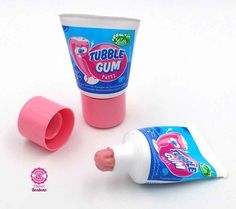 a tube of gum sitting next to a tube of toothpaste on a white surface