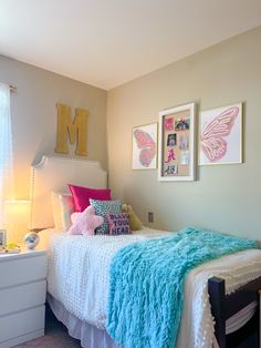 a bedroom with a bed, dresser and pictures on the wall