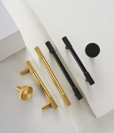 three different types of black and gold pens on a white surface next to each other