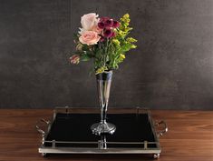 a silver vase with flowers on a black tray