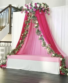 a bed covered in pink and white flowers on top of a wooden floor next to a stair case